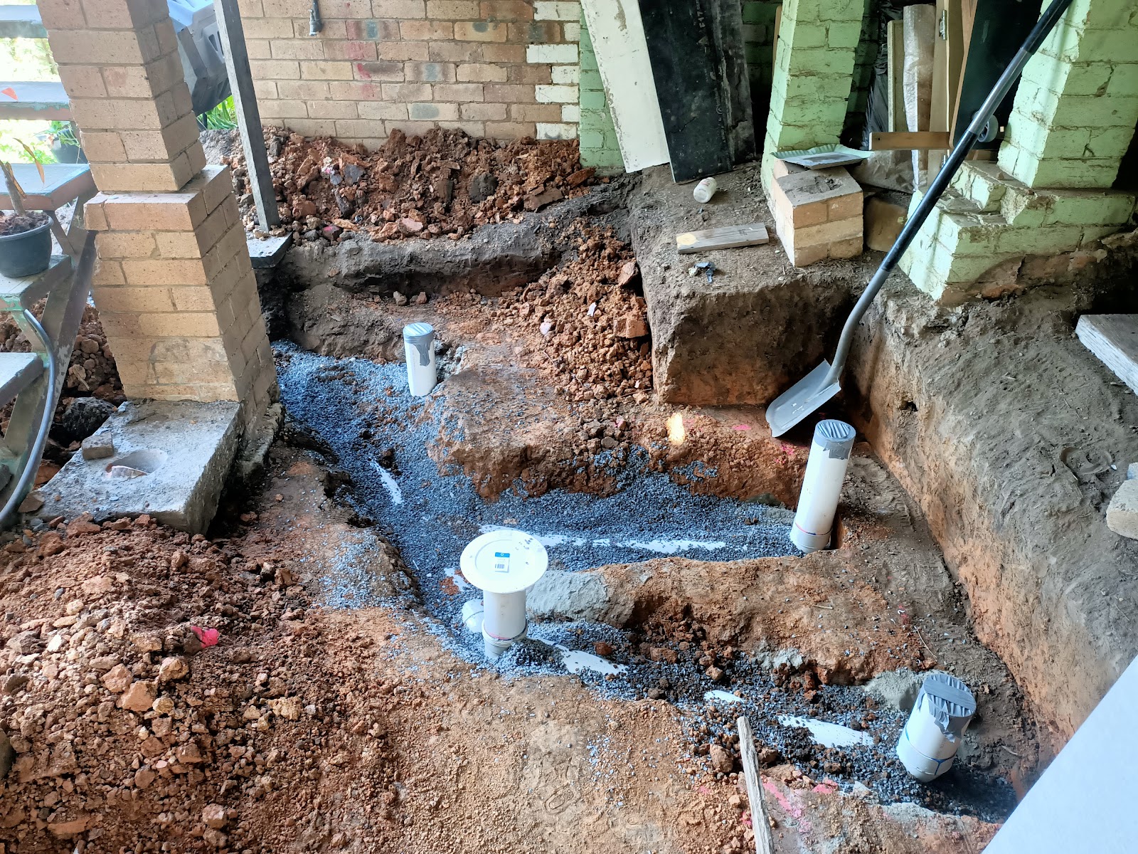 Under-slab drainage being roughed in, with new PVC risers set in blue metal