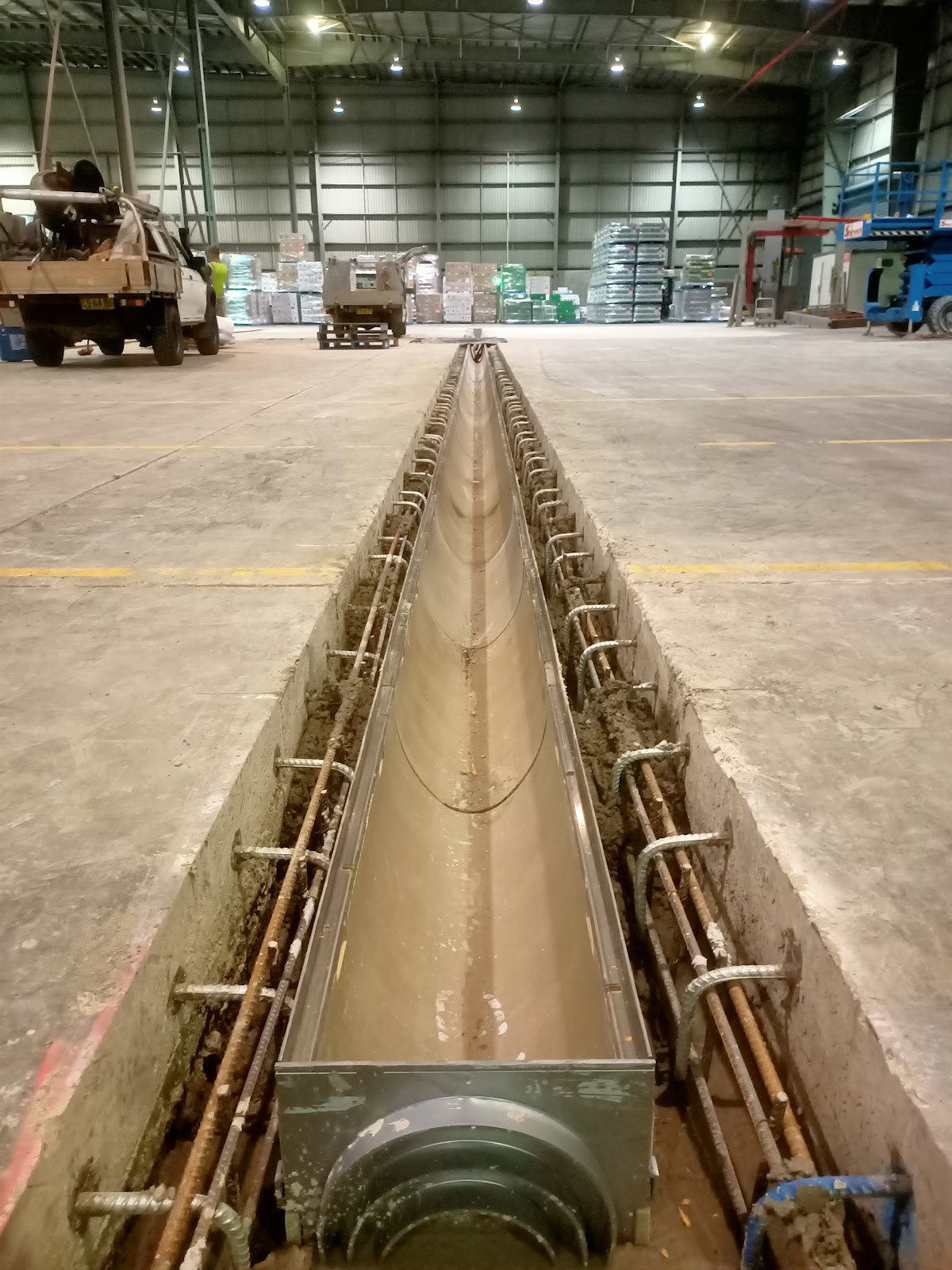 A long stainless trench drain set into a warehouse floor